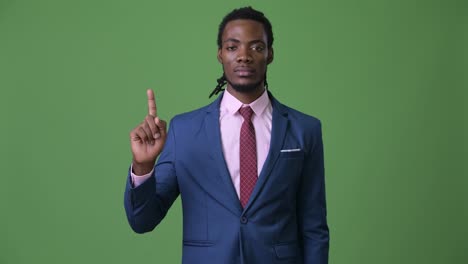 joven empresario africano guapo con dreadlocks contra un fondo verde