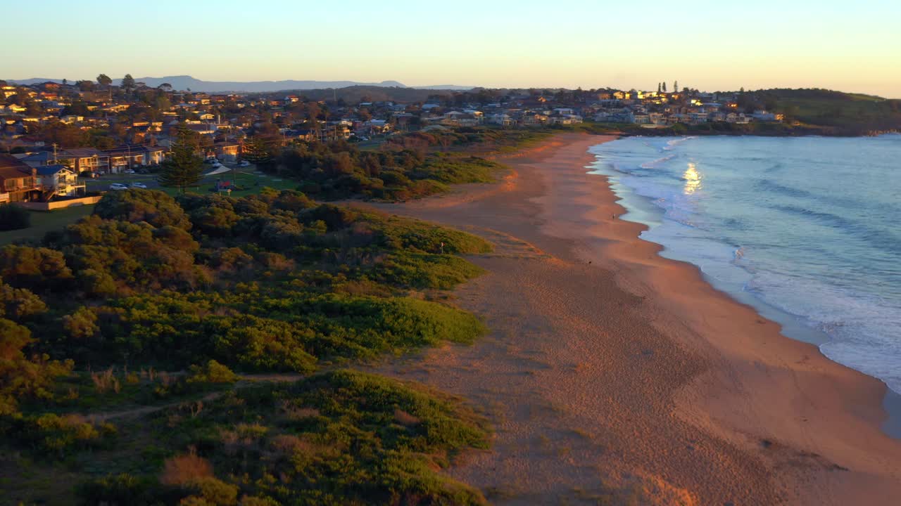 arena y vegetación con ciudad costera en jones beach cerca de las rocas de la catedral en kiama, nueva gales del sur, australia