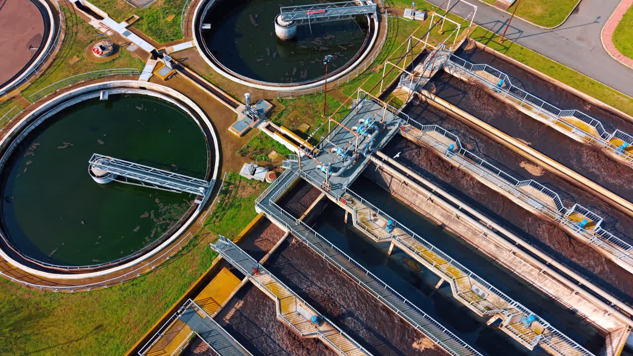 Industrial water treatment plant with circular clarifiers and basins. Aerial drone perspective of sewage treatment plant showing circular tanks and rectangular aeration units
