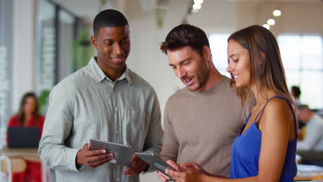 Equipo-De-Negocios-Multicultural-Con-Tabletas-Digitales-Reunidos-En-Una-Moderna-Oficina-Abierta.