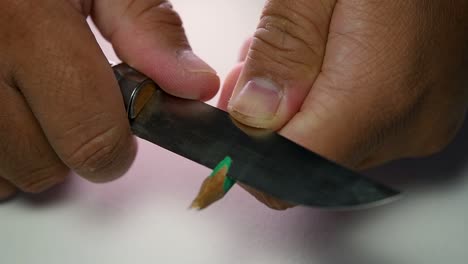 Footage-of-hands-slowly-sharpening-a-pencil-and-some-coloured-pencils-with-a-sharp-knife