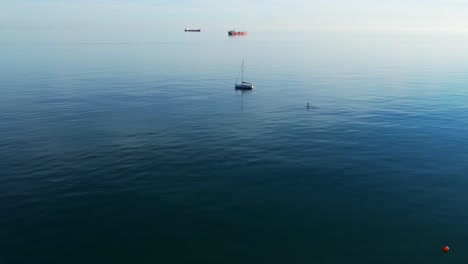 Yacht-Liegt-Nahe-Am-Strand,-Touristen-Schwimmen-Auf-Pfützenbrandung