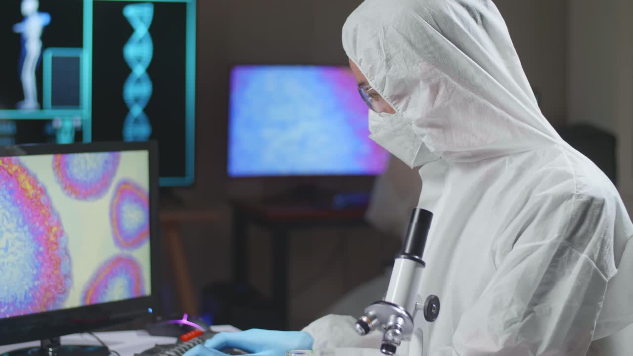 Asian Doctor In Protective Suit Working On Computer In A Modern Lab. Laboratory Assistant Workplace. The Concept Of Science And Medicine