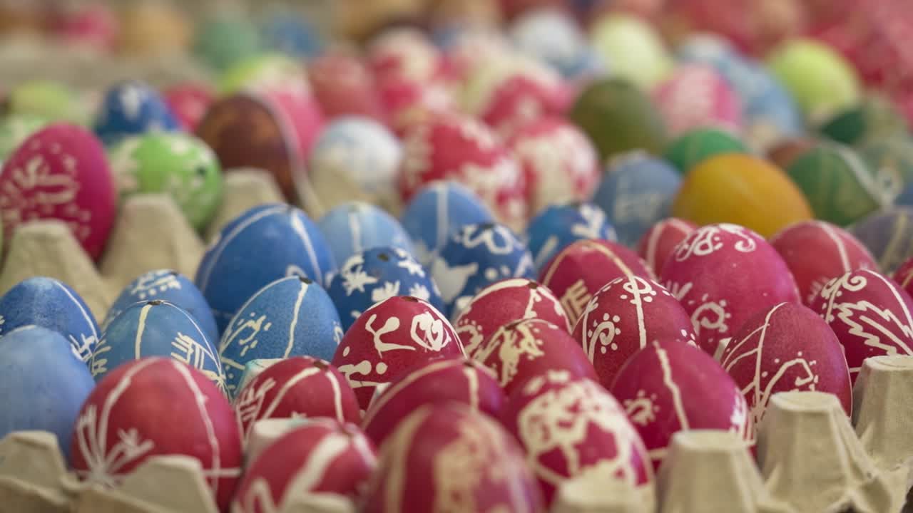 Rows of brightly dyed Easter eggs in vibrant red, blue and green hues in trays