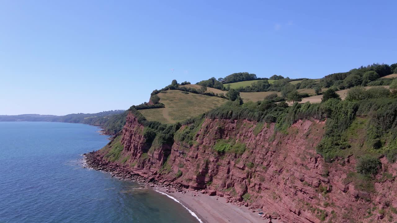 toma aérea ascendente inclinada hacia abajo de una hermosa costa con una playa escondida en el océano atlántico durante el cielo azul y la luz del sol