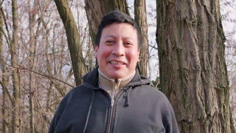 an ecuadorian man with short black hair laughing in the forest during a winter afternoon - medium shot, slow motion