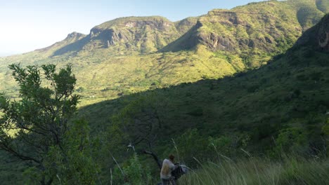 Un-Excursionista-Se-Pone-Una-Mochila-Mientras-Contempla-Las-Impresionantes-Vistas-De-Una-Montaña-Volcánica-Tropical-En-El-Este-De-África