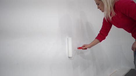 the-woman-painting-walls-with-roller-equipment-while-moving-in-apartment.-Renovating-new-house-and-improvement-concept