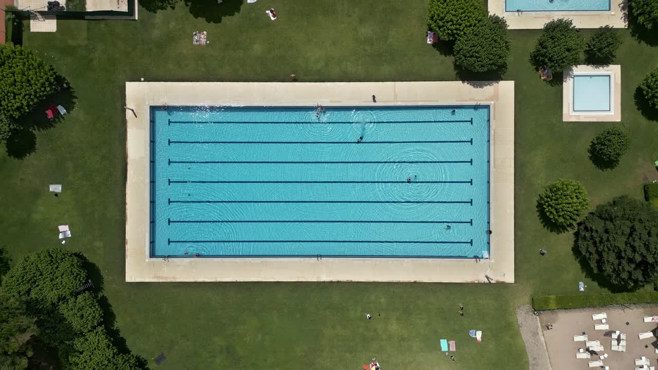 Uma piscina pública ao ar livre com pessoas aproveitando suas instalações.