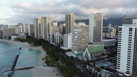 toma cinematográfica de drones de 4k de la playa de waikiki y los hoteles que la bordean durante el amanecer en un día nublado en oahu