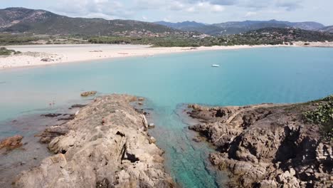 perfect picture book beach in south sardinia in chia with 2 rocks in turquoise water, drone