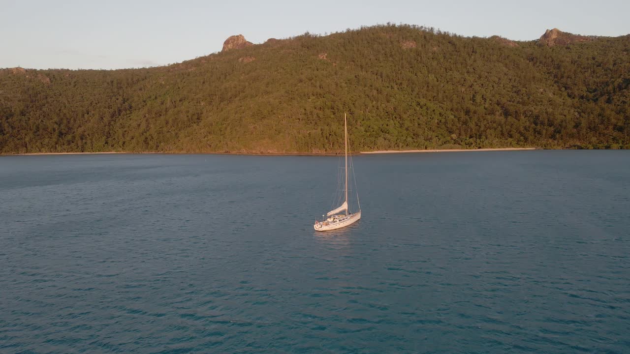 océano sereno con barco navegando cerca de las montañas forestales de la isla gancho en el parque nacional de las islas whitsunday, qld australia