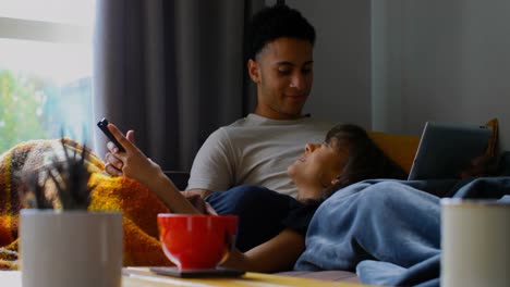 Joven-Pareja-Asiática-Usando-Teléfono-Móvil-Y-Tableta-Digital-En-La-Sala-De-Estar-En-Casa-4k