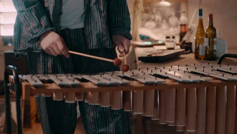 man plays the metallophone to make music in a blue paisley suit