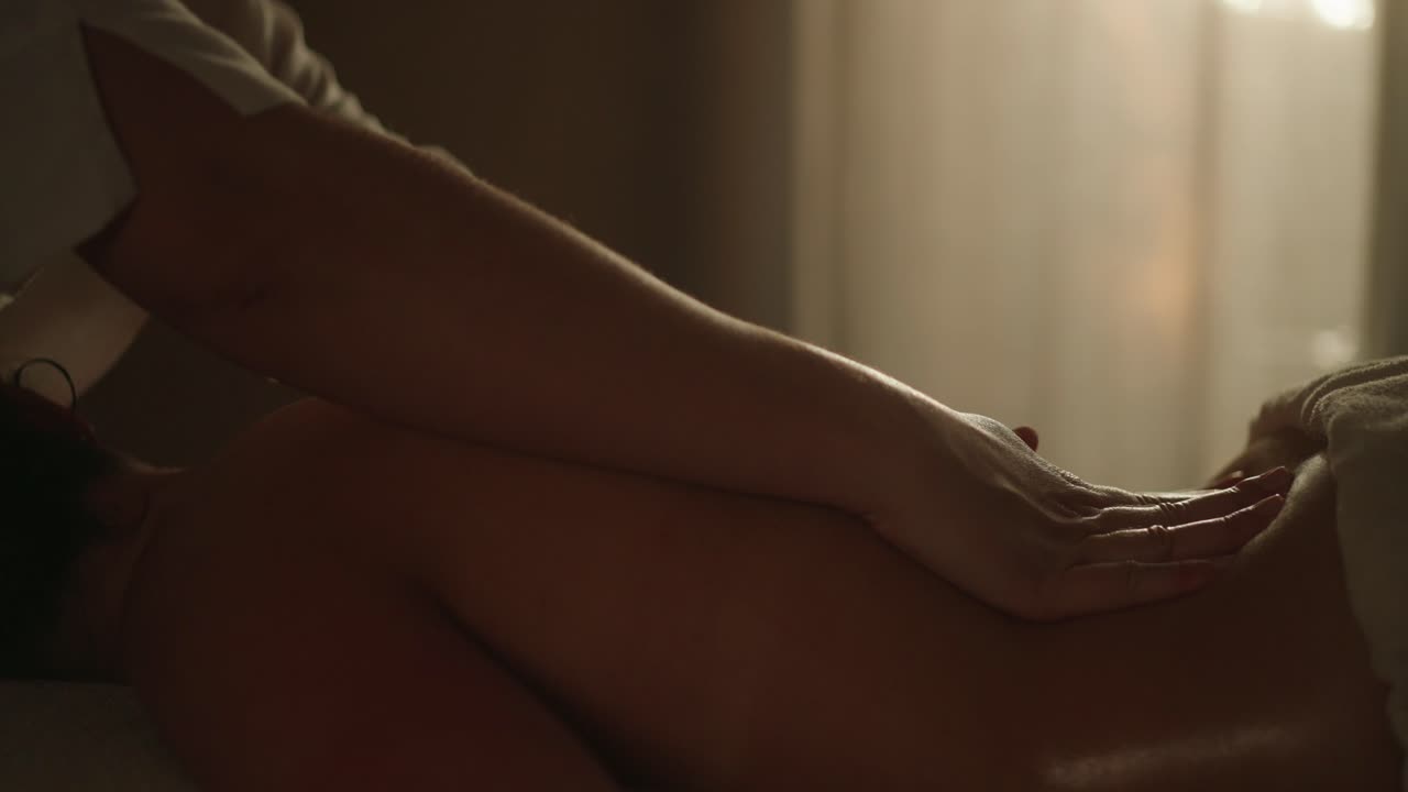 manos de masaje de espalda profesional en una habitación con poca luz