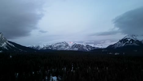 Aerial-descent-of-foggy-morning-snow-capped-mountains,-Alberta,-Canada