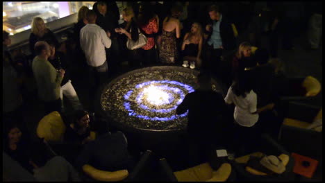 Rack-focus-of-adults-dancing-around-a-fire-at-a-rooftop-nightclub-in-San-Diego-California