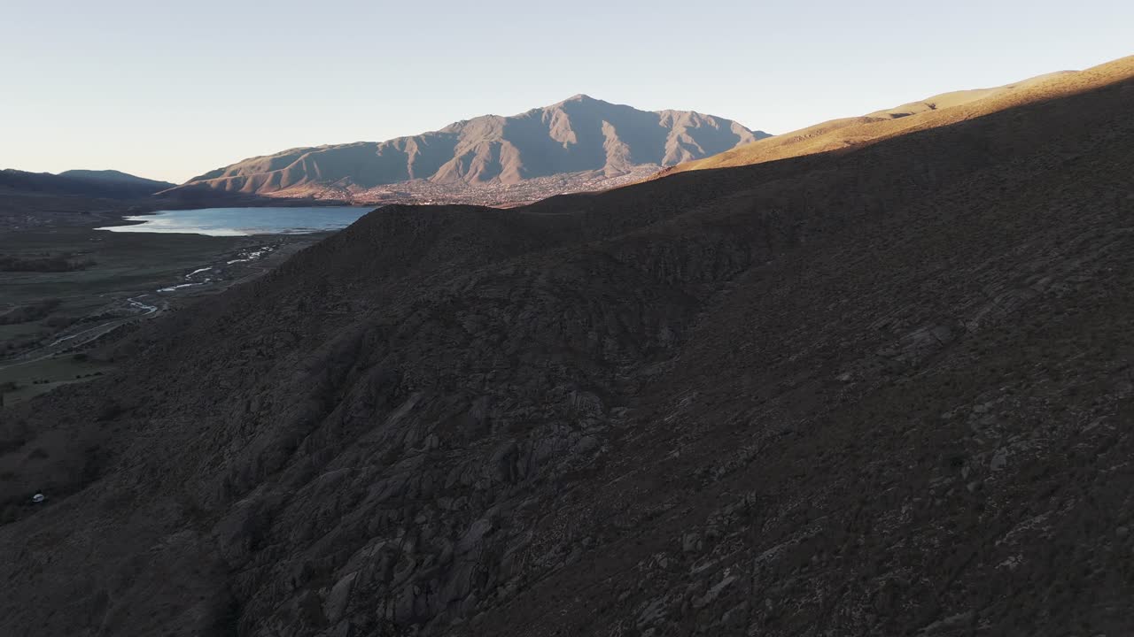 A Horse Traversing a Rugged Hillside Overlooking a Scenic Mountain Valley and Lake