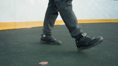 close-up of feet in motion, wearing tactical boots on a sports field, with yellow boundary line visible, showcasing dynamic athletic movement with foliage on the ground