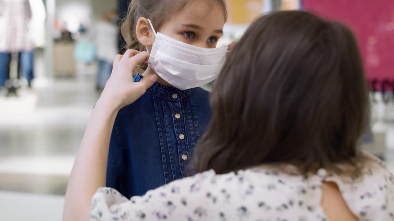 Mother putting a medical mask on her lovely daughter's face