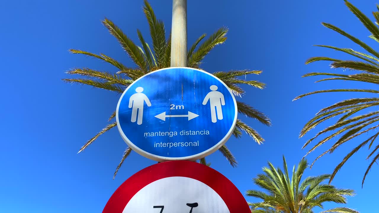 Spanish sign of corona virus to keep the distance with palm trees and blue sky in Marbella Spain, static shot 4K