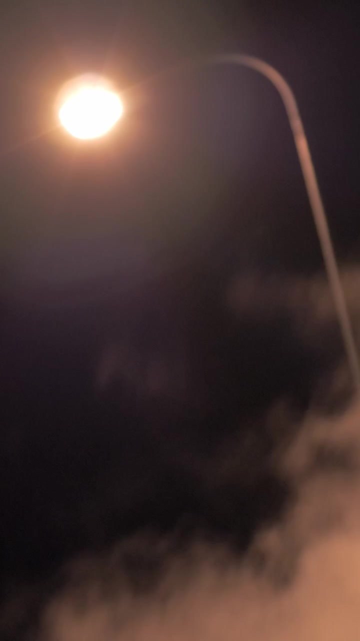 Poste de luz e fumaça condensada se espalhando ao ar livre à noite