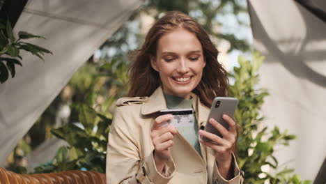 estudiante caucásica haciendo compras en línea en el teléfono inteligente al aire libre.