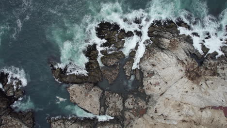 Vista-Aérea-De-Las-Olas-Del-Océano-Rompiendo-Entre-Las-Rocas