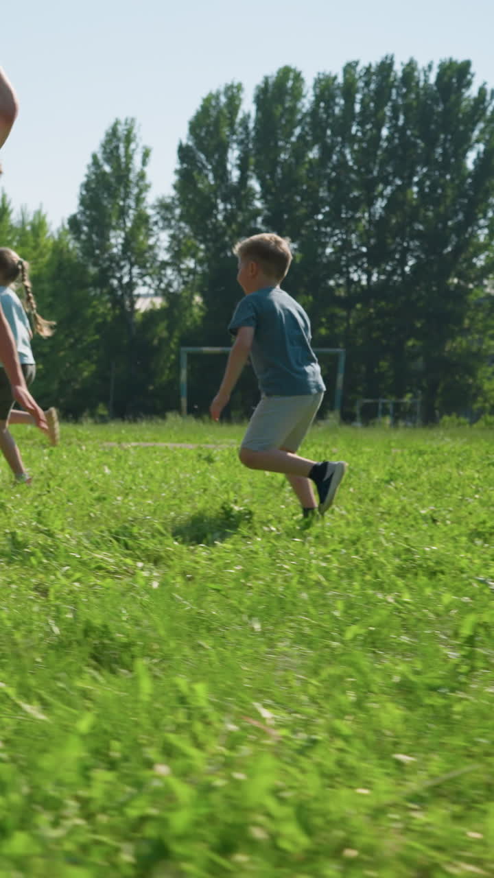 la familia disfruta de un juego de fútbol al aire libre en un día soleado mientras el hijo vestido de blanco dribla la pelota, sólo para que su hermano se deslice y patee la pelota en un momento lúdico en el campo cubierto de hierba.
