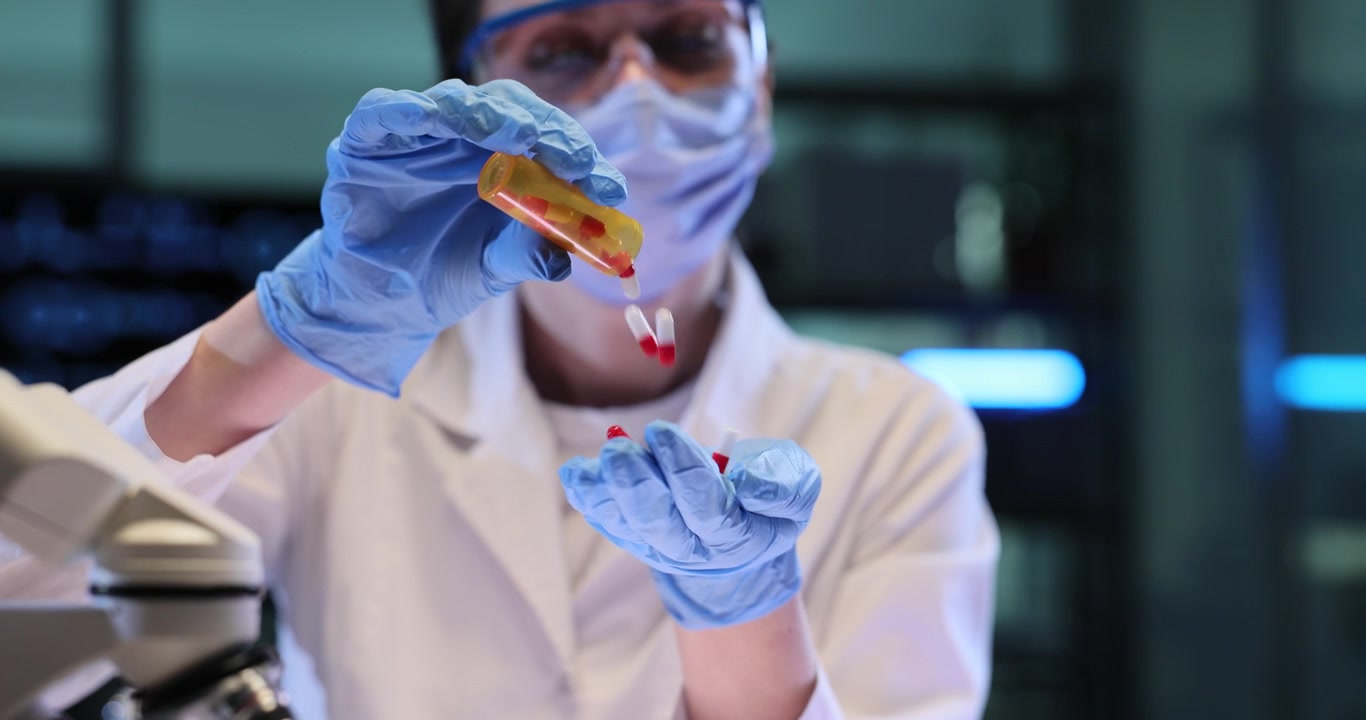 Woman scientist pours tablets from bottle into gloved hand in lab
