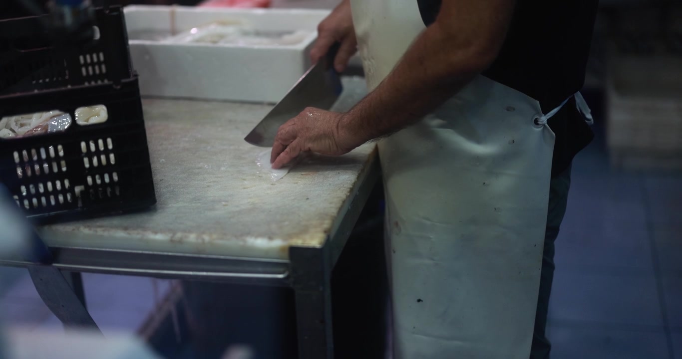 Fishmonger Cutting Fresh Squid with a Large Knife