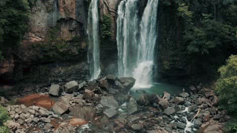 tourists on rocks admiring water gushing from nauyaca waterfalls in costa rica