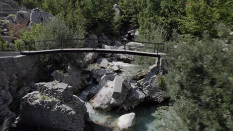 video with drone of "sam kolder" plane going back, through a bridge of the valbone river in albania, ascent road to valbones valley, video ends with horizon in the mountains