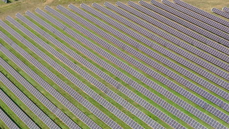 Aerial-forward-view-of-large-solar-farm-with-many-rows-of-solar-panels-creating-green,-renewable-energy-to-replace-fossil-fuels-and-to-power-clean-transition-to-fight-climate-change