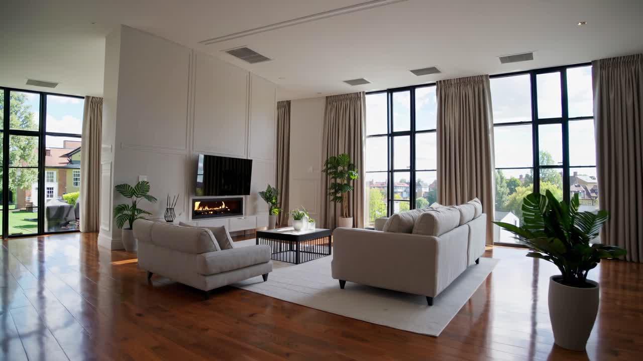 Wide-angle video of a modern living room with large windows, neutral tones, and sleek furniture