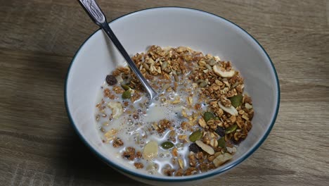 un zoom de un tazón de granola y leche de almendras recién vertido haciendo burbujas, semillas, frutas secas, desayuno saludable