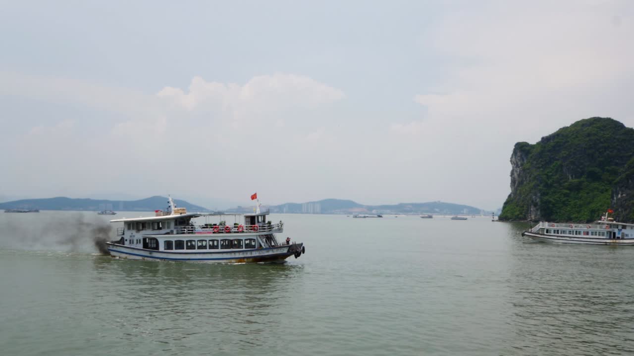 barco de pasajeros con humos oscuros viajando a lo largo de la bahía de halong en vietnam
