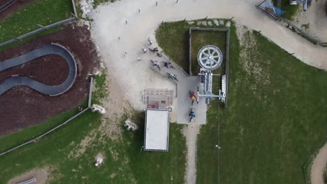 drone shot of a lift for mountain bikers in a bike trail park - view from above in bird's eye view slight downward movement - bikers standing at the lift