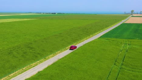 Antena-De-Un-Coche-Rojo-Que-Viaja-A-Través-De-Campos-Verdes-De-Normandía-Francia