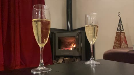 vídeo estático de dos copas de champán en una habitación romántica con una chimenea al fondo.