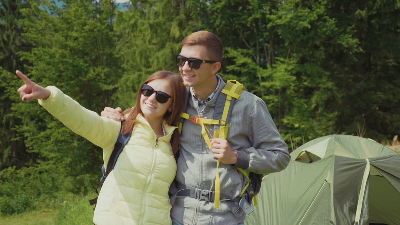pareja romántica en una caminata se paran en el campamento en el fondo de la carpa abrazan video hd