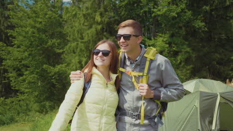 romantic couple in a hike they stand in the camping on the background of the tent embrace hd video