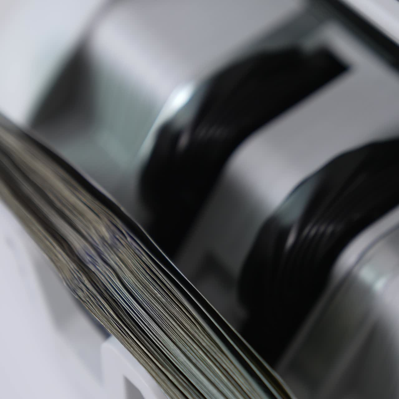 Rotating mechanism turning quickly hundred dollar US bills. Work of cash counting machine close up. Blurred background