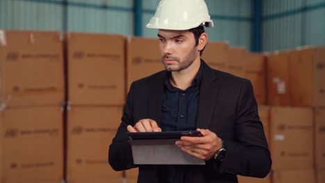 factory manager using tablet computer in warehouse or factory