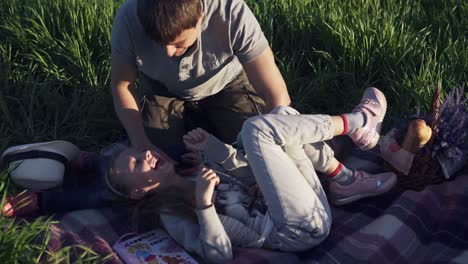 joven en el parque con sus hermosos hijos pequeños divirtiéndose. jugando con las niñas. se acuestan en la hierba, riendo, su padre las cosquillea. tiempo feliz en familia en la naturaleza