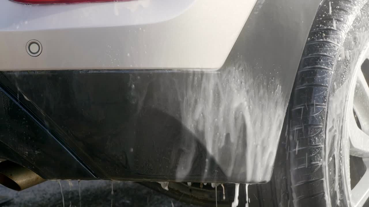 Rinsing off cleaning solution from plastic trim on rear bumper close up