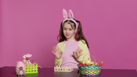 joyful schoolgirl with bunny ears waving hello in front of camera