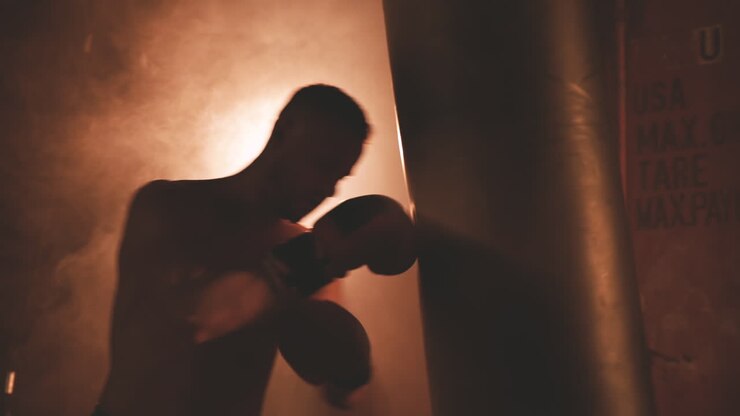 Pugile a torso nudo si riscalda colpendo il sacco da boxe