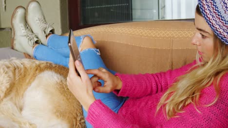 woman using digital tablet with her dog on sofa 4k