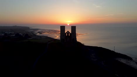 silhouette of reculver towers against orange sunset skies